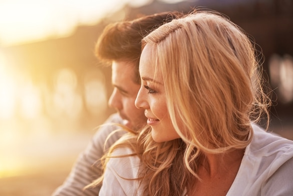 pretty-girl-cuddling-with-boyfriend-on-beach-at-santa-monica-with-shallow-depth-of-field-and-bright-warm-lens-flare