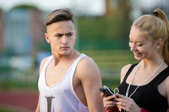 jealous-worried-man-peering-over-the-shoulder-of-his-girlfriend-while-she-is-talking-on-the-phone-smiling