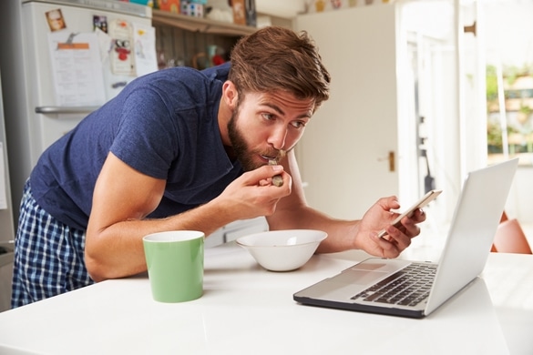 Man Eating Breakfast Whilst Using Mobile Phone And Laptop - Why Are Taurus Men So Secretive